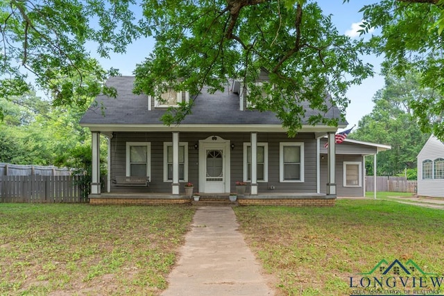 view of front of property with a porch, fence, and a front lawn