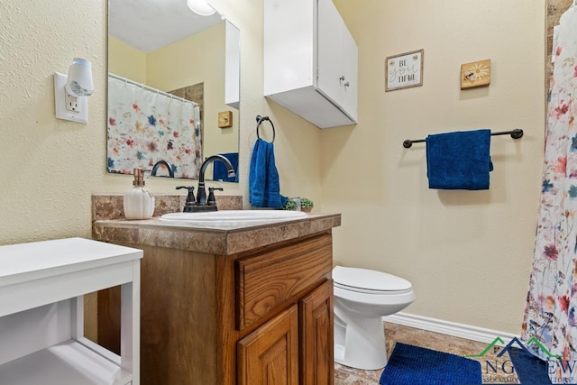 bathroom featuring vanity, toilet, and baseboards