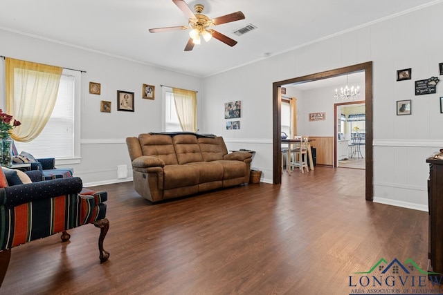 living room with dark wood-style flooring, visible vents, crown molding, and ceiling fan with notable chandelier