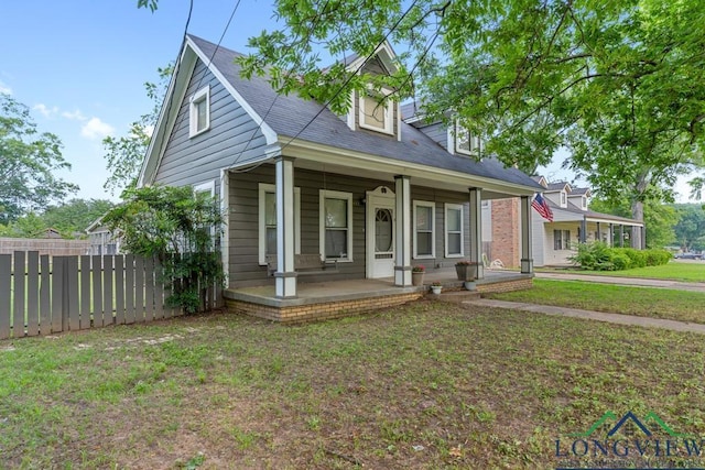 new england style home with a porch, a front yard, and fence