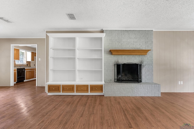 105 Bison Trl, Longview, TX 75601 - unfurnished living room with crown molding, wood finished floors, a textured ceiling, a fireplace, and wooden walls