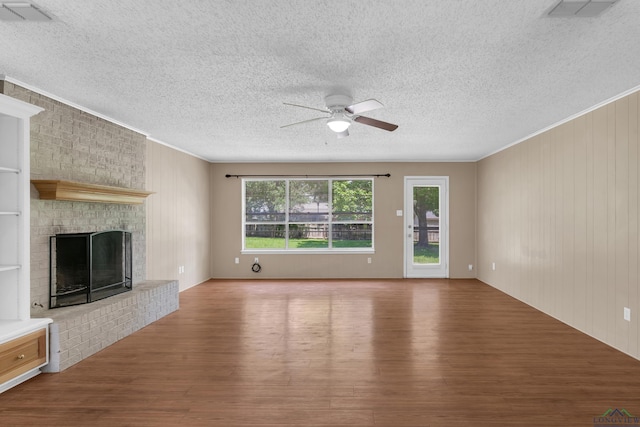 105 Bison Trl, Longview, TX 75601 - unfurnished living room featuring a ceiling fan, wood finished floors, crown molding, a textured ceiling, and a brick fireplace