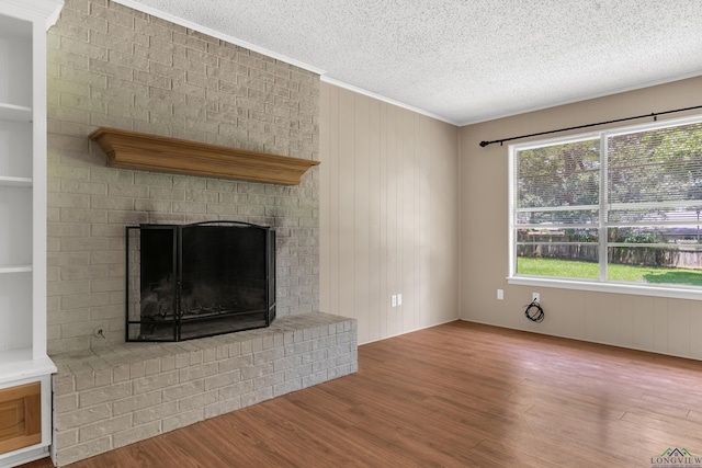 105 Bison Trl, Longview, TX 75601 - unfurnished living room with wood finished floors, a textured ceiling, a fireplace, and ornamental molding