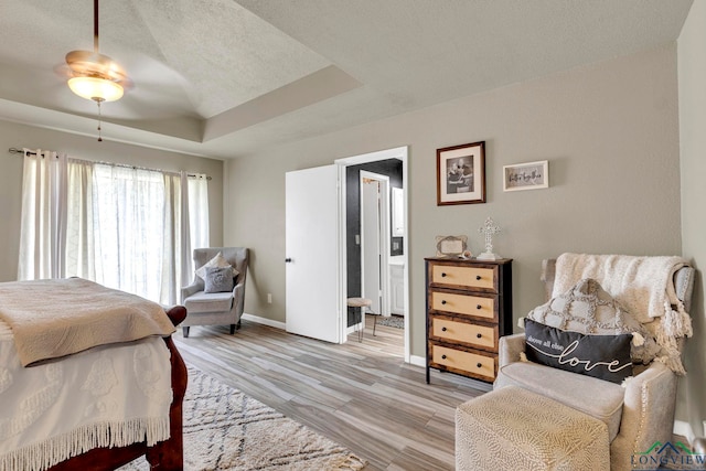 602 Pierce St, Lindale, TX 75771 - bedroom featuring a raised ceiling, baseboards, light wood-style flooring, a textured ceiling, and ensuite bathroom