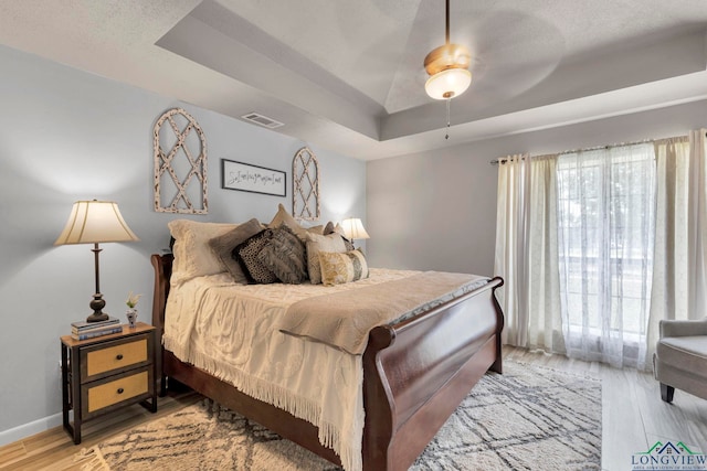 602 Pierce St, Lindale, TX 75771 - bedroom with a tray ceiling, light wood-style flooring, baseboards, and ceiling fan