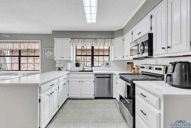 602 Pierce St, Lindale, TX 75771 - kitchen with appliances with stainless steel finishes, a peninsula, ornamental molding, tasteful backsplash, and white cabinets