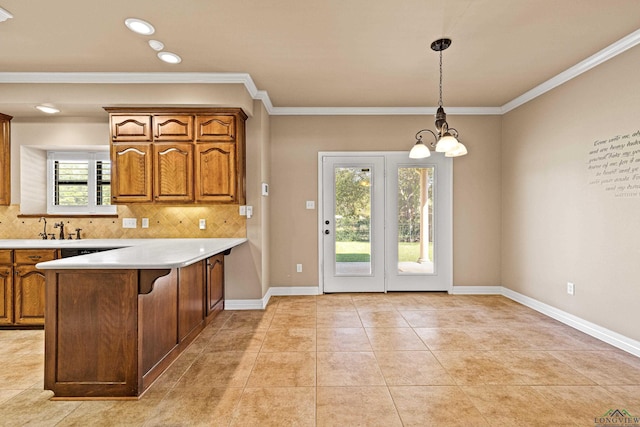 kitchen with a notable chandelier, kitchen peninsula, pendant lighting, decorative backsplash, and ornamental molding