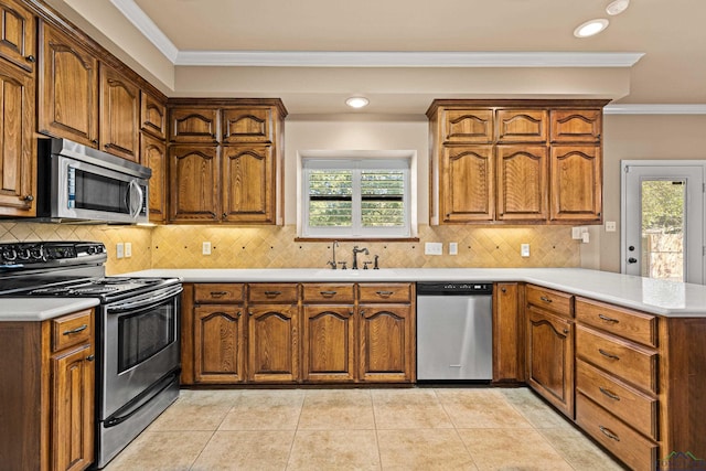 kitchen with sink, light tile patterned floors, ornamental molding, appliances with stainless steel finishes, and kitchen peninsula