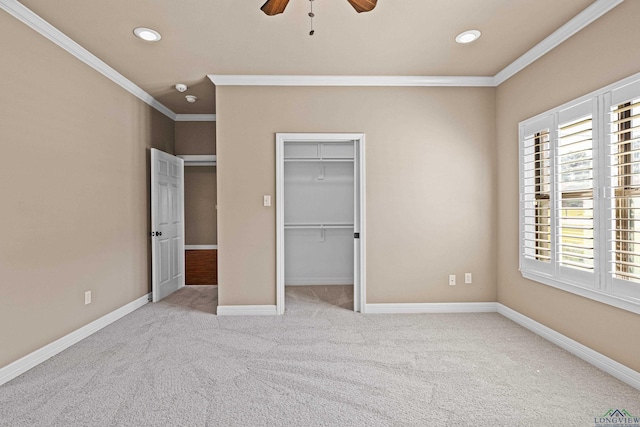 unfurnished bedroom with ceiling fan, a spacious closet, crown molding, light carpet, and a closet