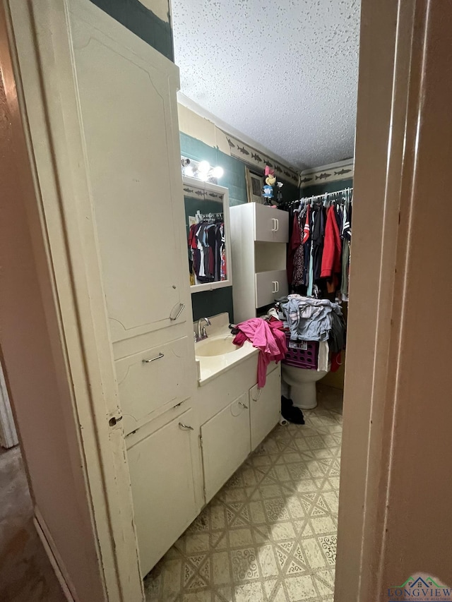 bathroom with a textured ceiling, vanity, and toilet