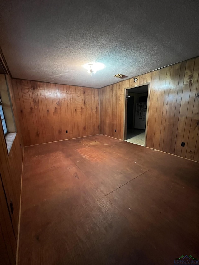 basement featuring wood walls and a textured ceiling