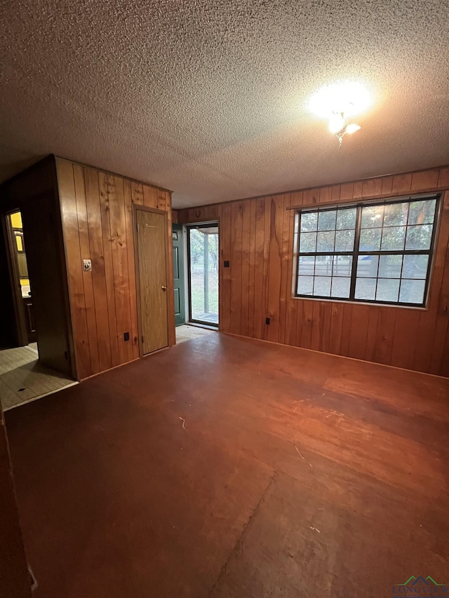 empty room featuring a textured ceiling and wooden walls