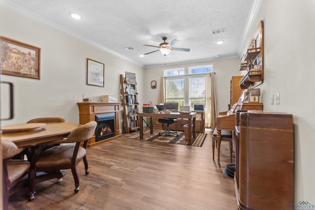 1767 County Road 3840, Hawkins, TX 75765 - home office with a ceiling fan, a warm lit fireplace, wood finished floors, crown molding, and a textured ceiling