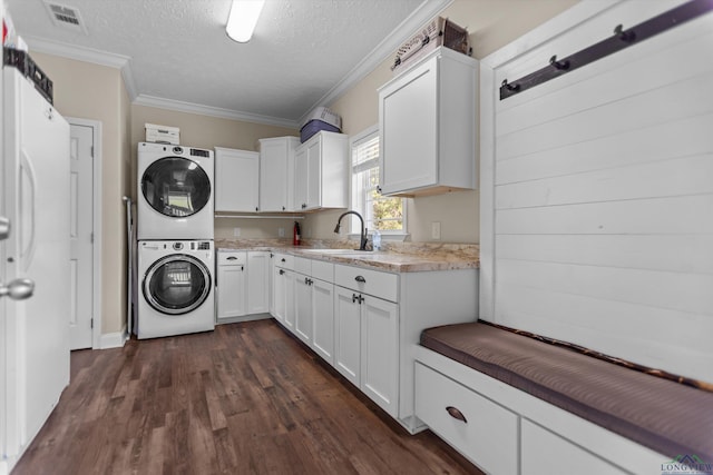1767 County Road 3840, Hawkins, TX 75765 - laundry area featuring stacked washer / dryer, cabinet space, ornamental molding, dark wood-type flooring, and a textured ceiling