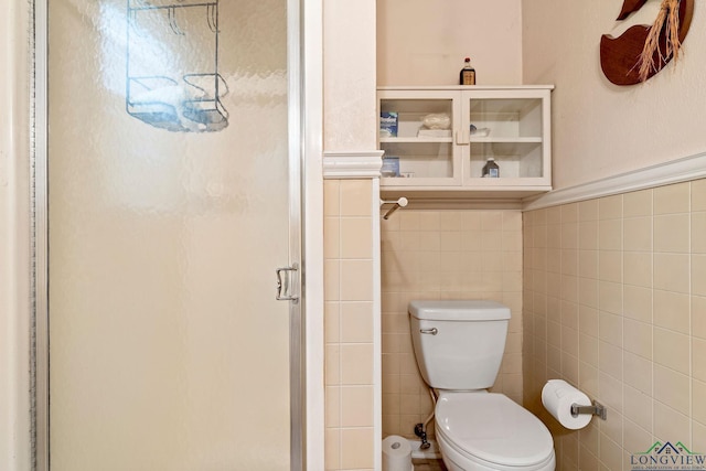 full bath with toilet, a shower stall, and tile walls