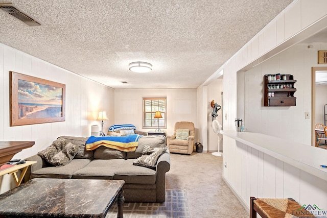 living room featuring visible vents, a textured ceiling, and light colored carpet