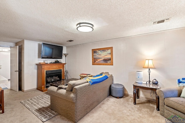 living room featuring light carpet, a fireplace, visible vents, and a textured ceiling