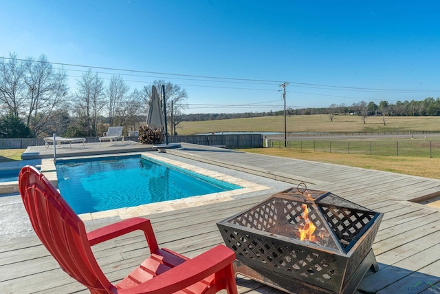 view of pool with a rural view, a deck, and an outdoor fire pit