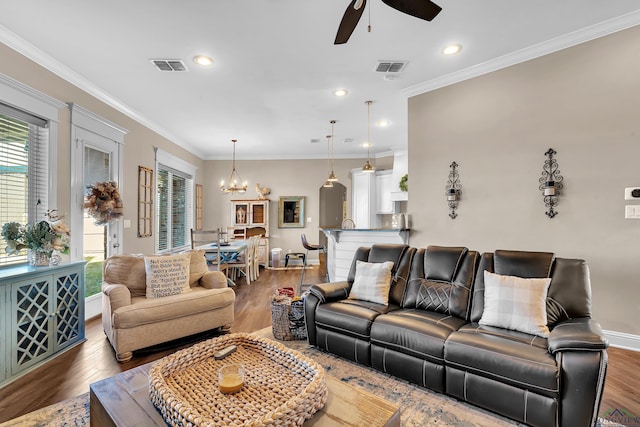 living room featuring crown molding, dark hardwood / wood-style flooring, and ceiling fan with notable chandelier