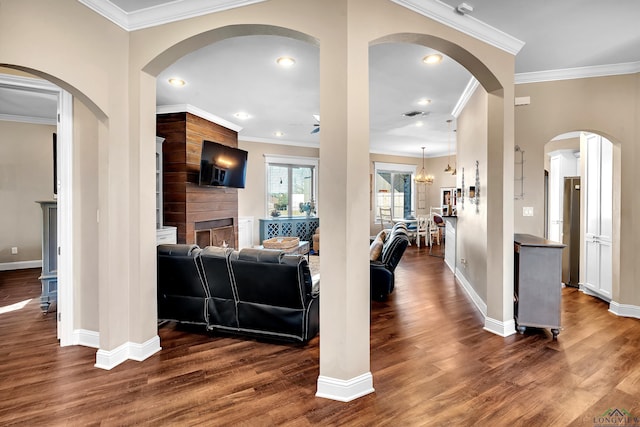 living room with ceiling fan with notable chandelier, dark wood-type flooring, and crown molding