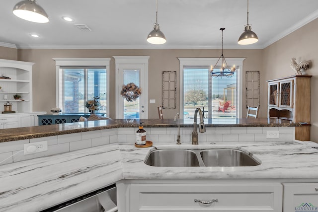 kitchen featuring white cabinetry, sink, hanging light fixtures, an inviting chandelier, and ornamental molding