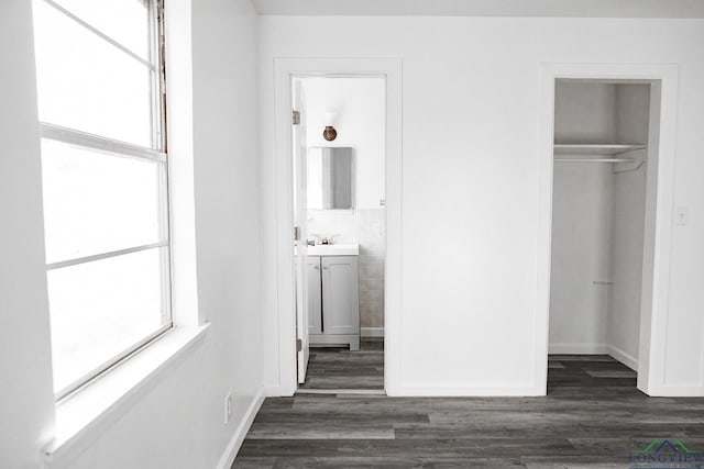 unfurnished bedroom with ensuite bath, sink, dark hardwood / wood-style flooring, and a closet