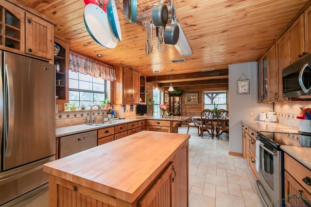 kitchen featuring appliances with stainless steel finishes, decorative light fixtures, wood ceiling, and sink