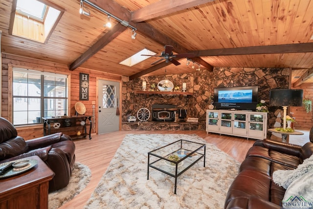 living room with a wood stove, ceiling fan, rail lighting, hardwood / wood-style floors, and wooden walls