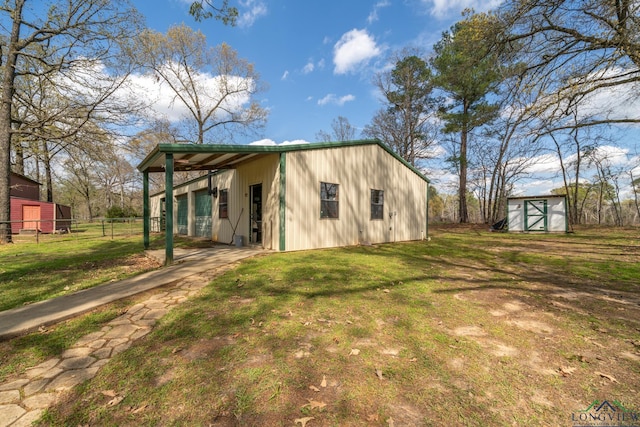 rear view of property featuring a yard and a storage unit