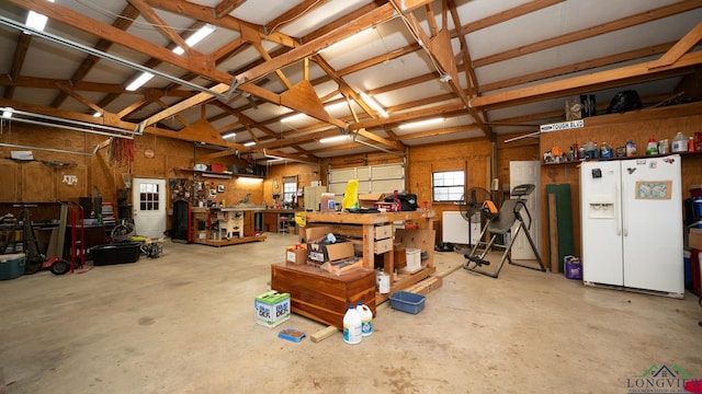 garage with a workshop area and white fridge with ice dispenser