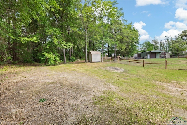 view of yard with a garage, a storage unit, an outbuilding, and fence