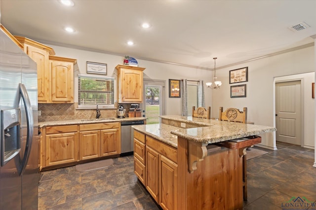 kitchen featuring stainless steel appliances, a sink, backsplash, a chandelier, and a kitchen bar