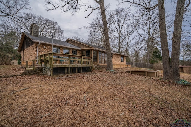 rear view of house with a deck, brick siding, and a chimney