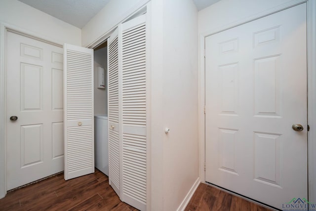 corridor with a textured ceiling, baseboards, and dark wood-type flooring