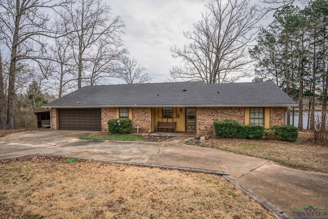 view of front facade with brick siding, a chimney, a shingled roof, concrete driveway, and a garage