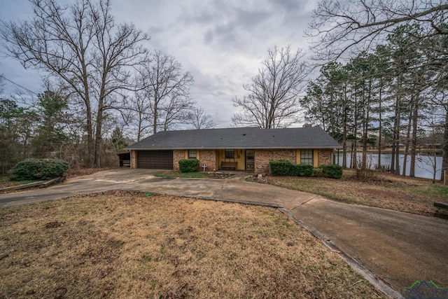 view of front of home featuring an attached garage, brick siding, a water view, driveway, and a front yard