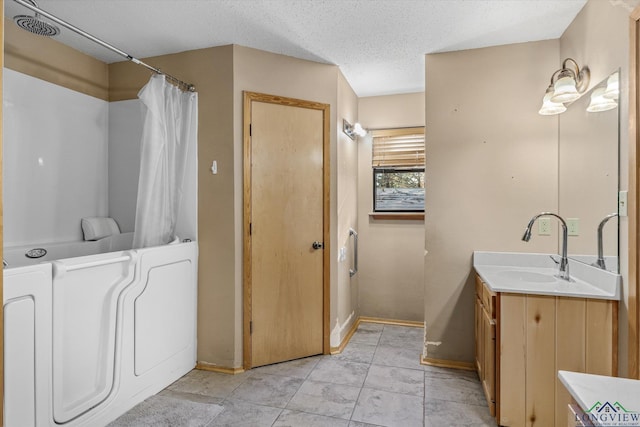 bathroom featuring a textured ceiling, vanity, and washer / clothes dryer