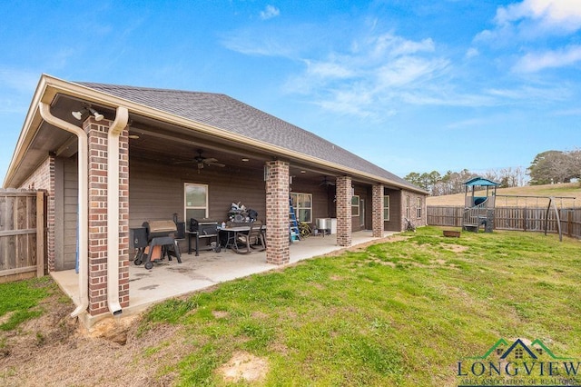 rear view of property featuring ceiling fan, a yard, a patio area, a playground, and brick siding