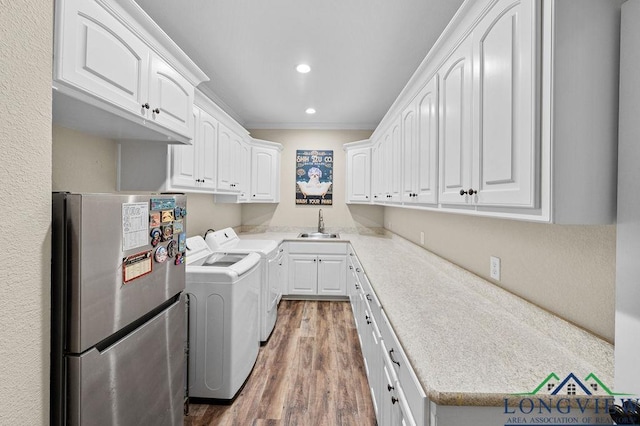 washroom with wood finished floors, washing machine and clothes dryer, crown molding, a sink, and recessed lighting