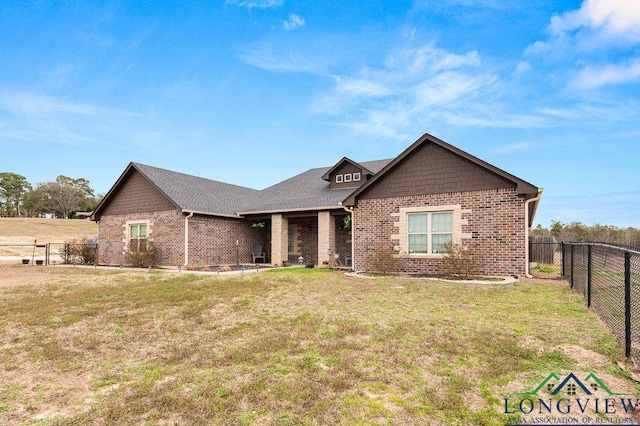 view of front of home with fence private yard, brick siding, and a front lawn