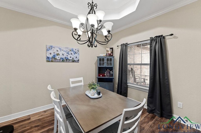 dining room featuring dark wood-style flooring, crown molding, a notable chandelier, a raised ceiling, and baseboards