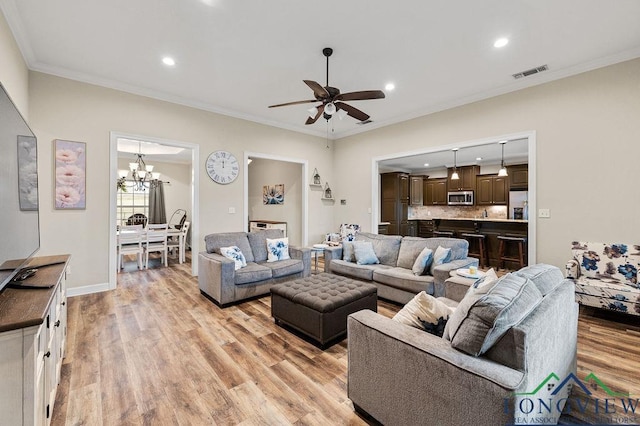 living room with light wood finished floors, visible vents, crown molding, and recessed lighting