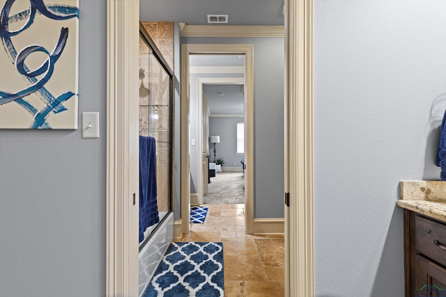 1600 Olympic Dr, Longview, TX 75605 - full bath with stone tile floors, vanity, ornamental molding, baseboards, and enclosed tub / shower combo