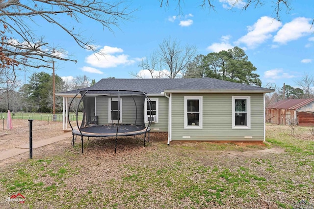 rear view of house with a trampoline and a lawn