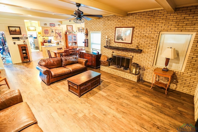 living room with a fireplace, beam ceiling, light hardwood / wood-style floors, and brick wall