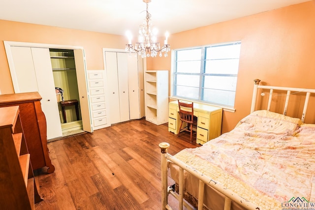 bedroom featuring multiple closets, a chandelier, and dark hardwood / wood-style floors