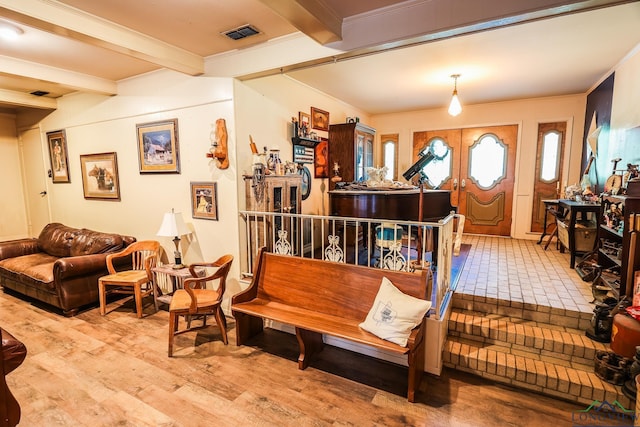 interior space featuring beam ceiling, light wood-type flooring, and ornamental molding