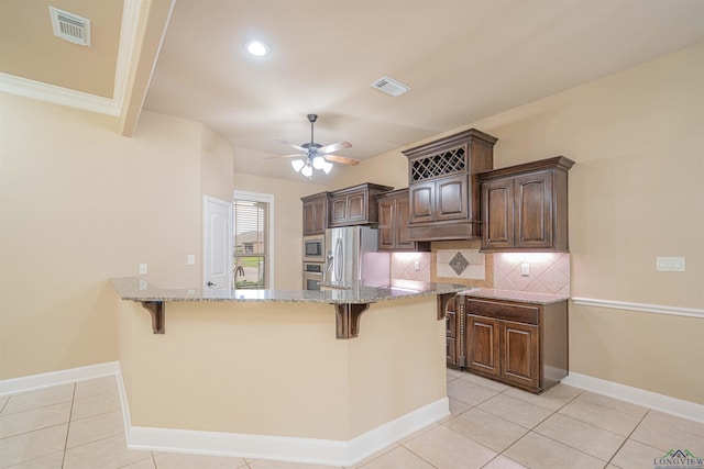 2532 Windmill Ln, Longview, TX 75601 - kitchen with stainless steel appliances, a kitchen bar, light stone counters, ceiling fan, and dark brown cabinets