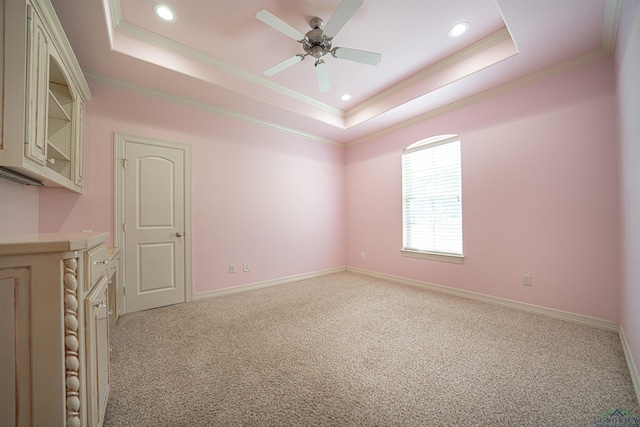 unfurnished room with baseboards, a raised ceiling, crown molding, and light colored carpet