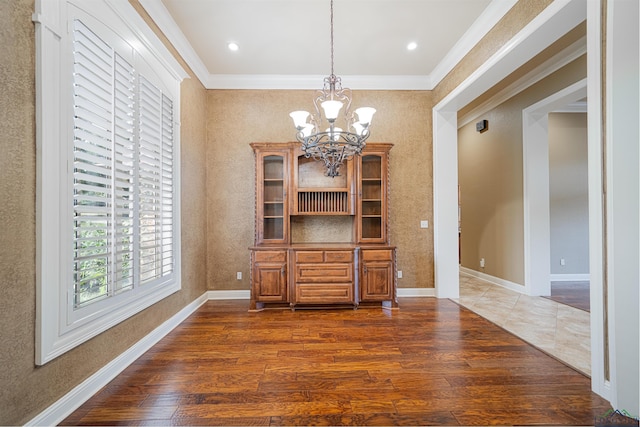 dining room with a notable chandelier, crown molding, baseboards, and wood finished floors